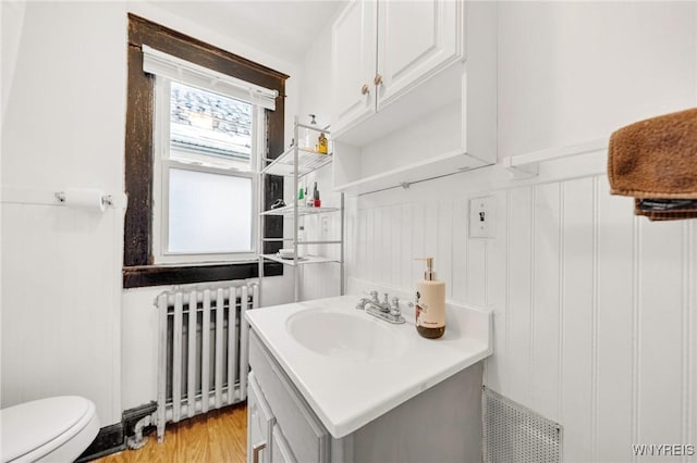 2486 Willow Ave, Niagara Falls, NY 14305 - bathroom with toilet, vanity, radiator, and wood finished floors