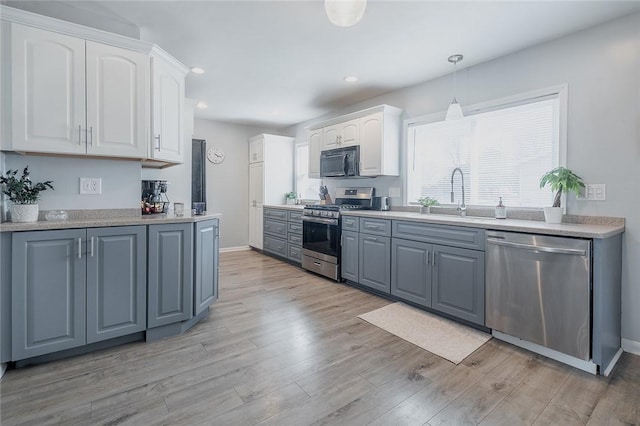120 Westmont Ave, Elmira, NY 14905 - kitchen with pendant lighting, light wood-style flooring, white cabinets, a sink, and stainless steel appliances