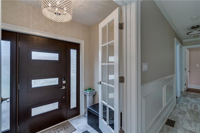 22036 Riverbend Dr W, Le Ray, NY 13601 - foyer with a decorative wall, visible vents, a chandelier, crown molding, and wainscoting