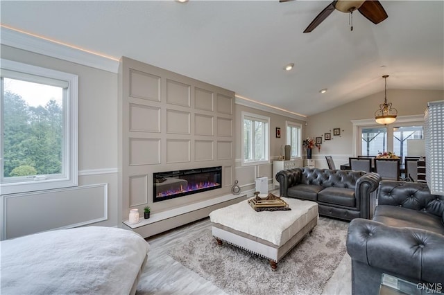22036 Riverbend Dr W, Le Ray, NY 13601 - living area featuring a decorative wall, light wood finished floors, ceiling fan, lofted ceiling, and a glass covered fireplace