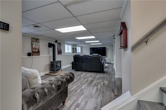 22036 Riverbend Dr W, Le Ray, NY 13601 - living room with visible vents, baseboards, wood finished floors, a drop ceiling, and a wood stove