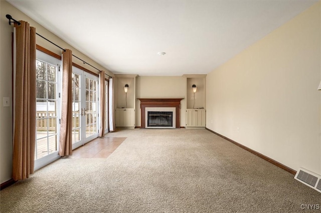 unfurnished living room with a fireplace with flush hearth, baseboards, light colored carpet, and visible vents