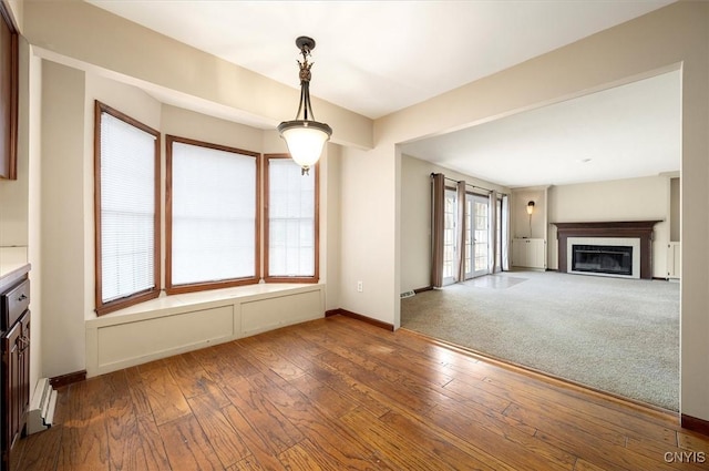 interior space with baseboards, a glass covered fireplace, and hardwood / wood-style flooring