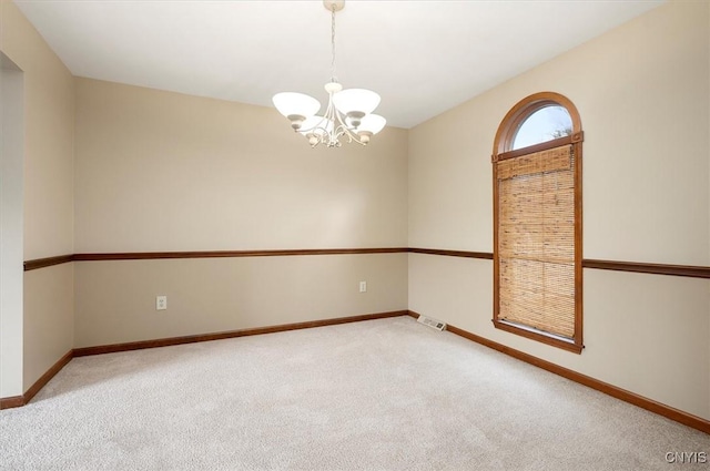 carpeted spare room with an inviting chandelier, baseboards, and visible vents