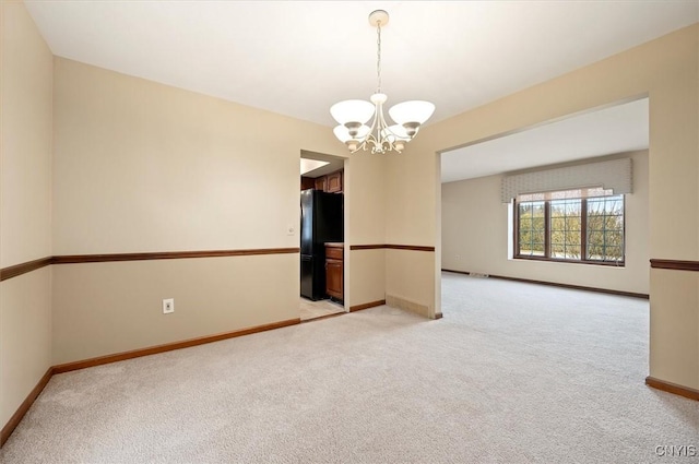 empty room with light carpet, baseboards, and a notable chandelier
