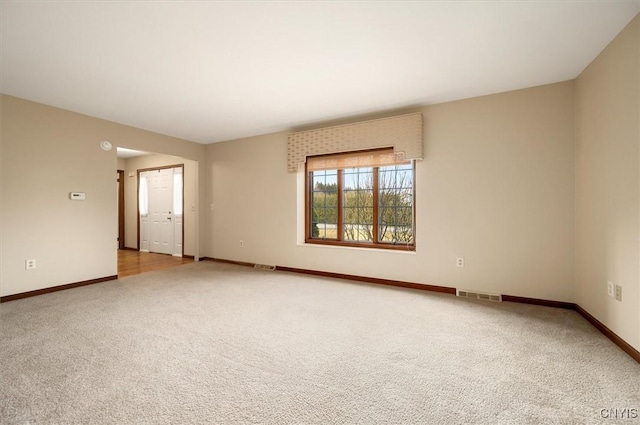 spare room with baseboards, visible vents, and light carpet