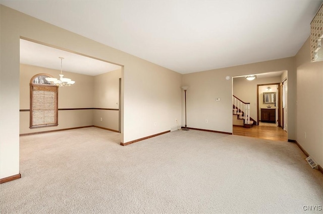 carpeted empty room with a notable chandelier, baseboards, stairs, and visible vents
