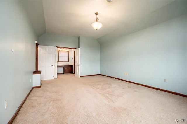 unfurnished bedroom featuring light colored carpet, vaulted ceiling, and baseboards