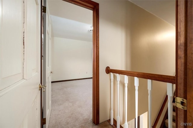 hall featuring baseboards, an upstairs landing, and carpet floors