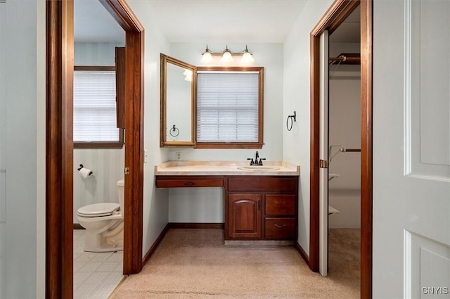 bathroom with baseboards, toilet, and vanity