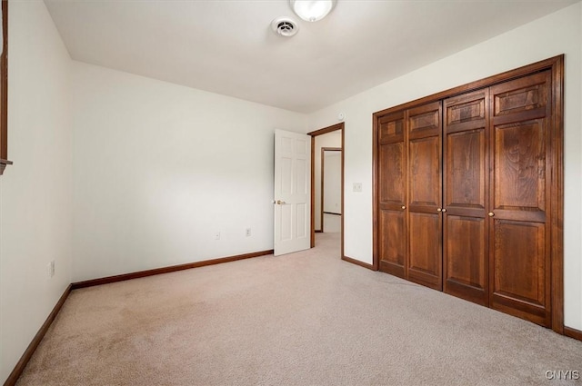 unfurnished bedroom featuring baseboards, visible vents, a closet, and light colored carpet