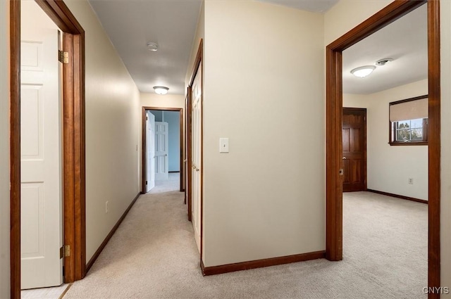 hallway featuring baseboards and light colored carpet