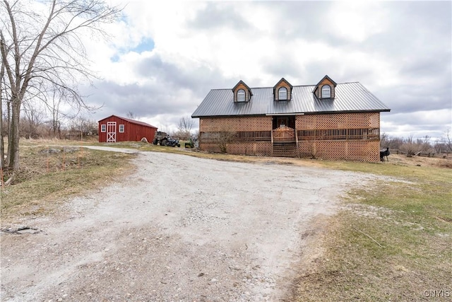 view of front of home with an outbuilding, driveway, a barn, and metal roof