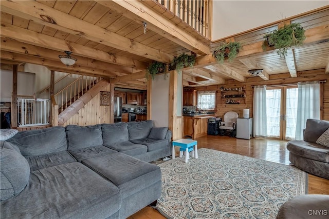 living area featuring light wood-style flooring, wood ceiling, wooden walls, and beamed ceiling