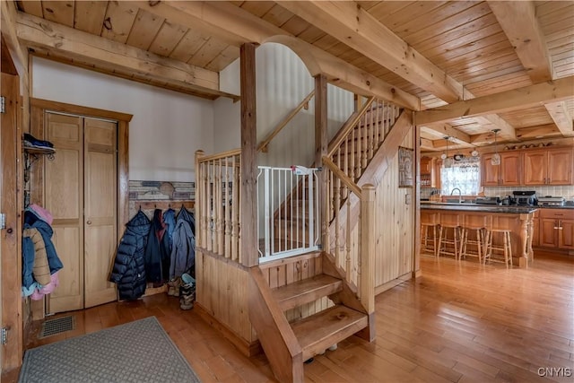 stairs featuring hardwood / wood-style floors, visible vents, wooden ceiling, and beam ceiling