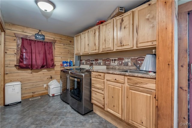 washroom with a sink, cabinet space, independent washer and dryer, and wood walls