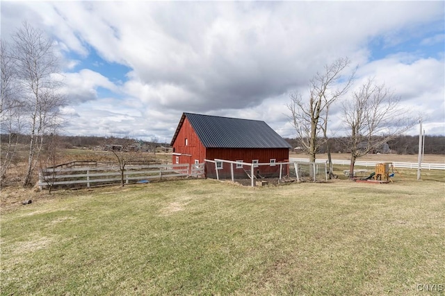 view of yard with a rural view, an outbuilding, fence, and a barn