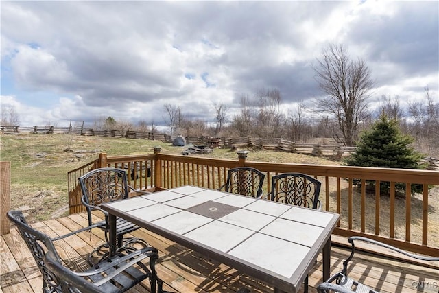 wooden deck with outdoor dining space, fence, and a rural view