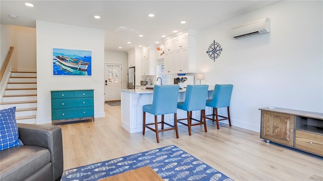 5170 Sunnyside Rd, Italy, NY 14507 - interior space featuring stairway, freestanding refrigerator, light wood-style floors, an AC wall unit, and recessed lighting