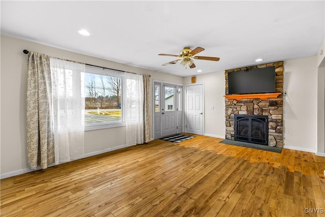 unfurnished living room with wood-type flooring, a ceiling fan, and baseboards