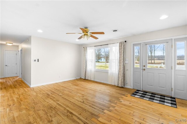 foyer entrance with baseboards, a ceiling fan, visible vents, and light wood-type flooring