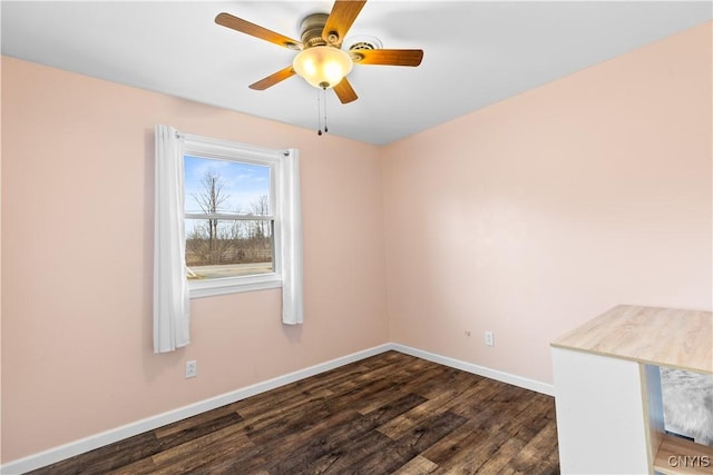 unfurnished room with baseboards, ceiling fan, and dark wood-type flooring