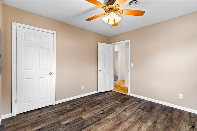 unfurnished bedroom with baseboards, dark wood-style flooring, visible vents, and a ceiling fan