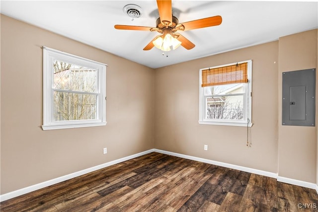unfurnished room featuring dark wood finished floors, a wealth of natural light, baseboards, and electric panel