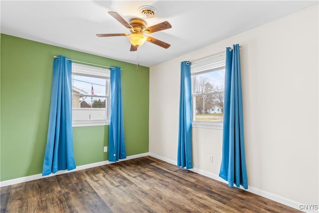 spare room with baseboards, wood finished floors, and plenty of natural light