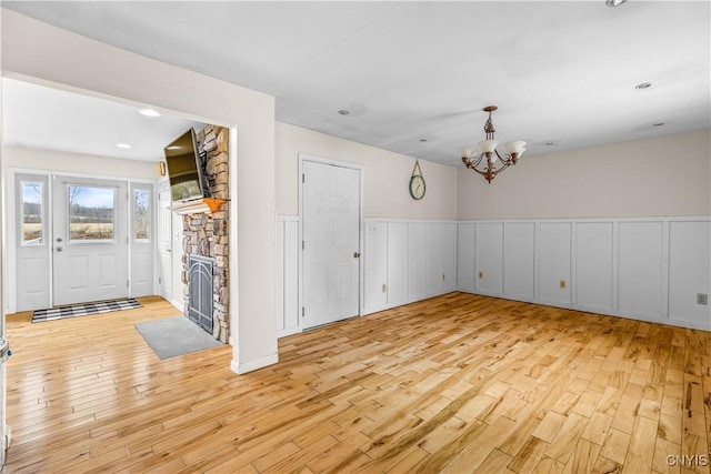 empty room featuring light wood-style flooring, a notable chandelier, and wainscoting