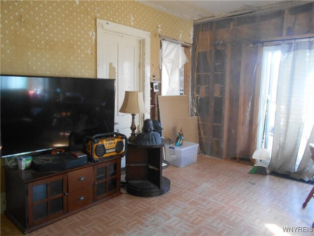 living room featuring wallpapered walls, crown molding, and parquet flooring