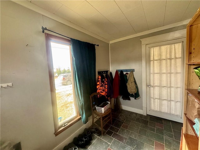 entryway with baseboards, crown molding, and stone tile flooring