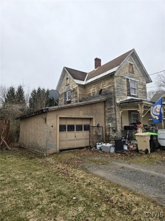 view of side of home with driveway, an attached garage, and a chimney