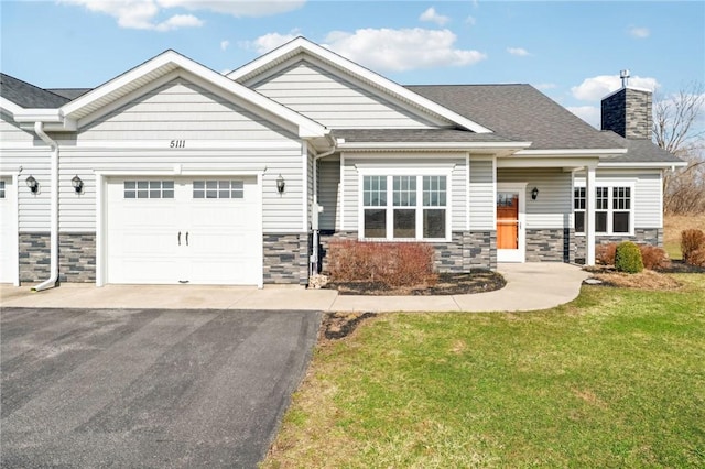 craftsman house with a garage, driveway, stone siding, and a front yard