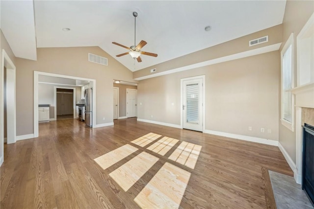 unfurnished living room featuring a fireplace with flush hearth, wood finished floors, visible vents, and a ceiling fan