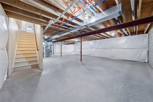 unfinished below grade area featuring heating unit and stairway