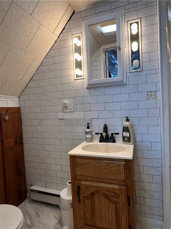 bathroom featuring toilet, vanity, vaulted ceiling, and a baseboard heating unit