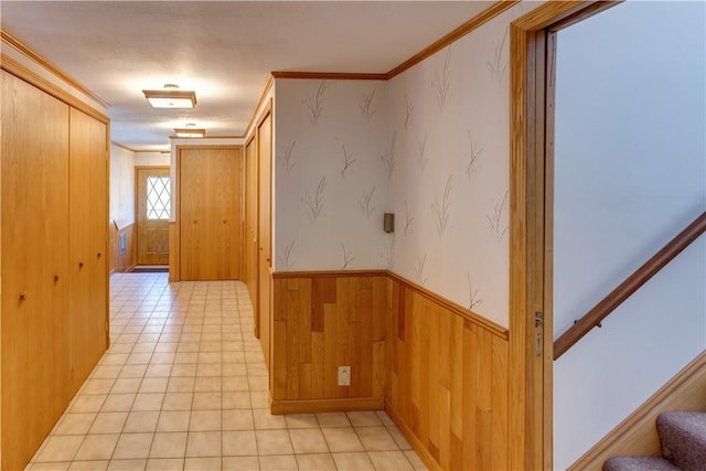corridor featuring wainscoting, crown molding, wood walls, and stairway