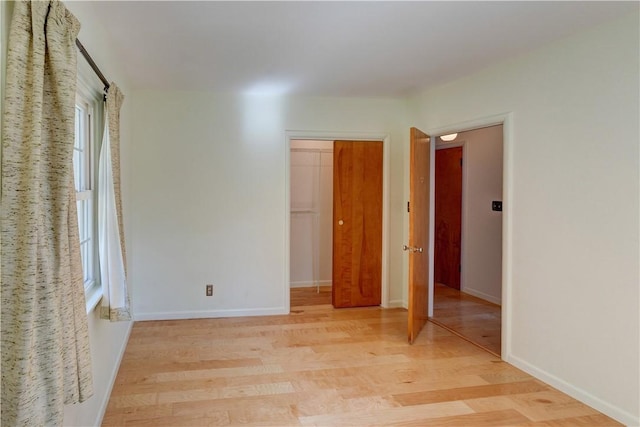 unfurnished room with baseboards and light wood-type flooring