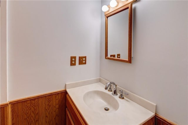 bathroom with a wainscoted wall, vanity, and wood walls
