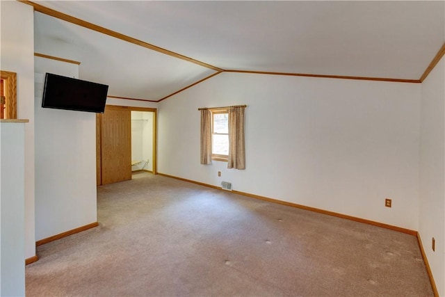 carpeted spare room featuring baseboards, lofted ceiling, visible vents, and ornamental molding