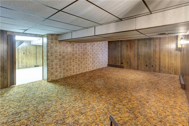 finished basement featuring carpet, wooden walls, and a paneled ceiling