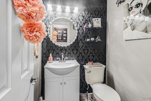 half bathroom with wallpapered walls, toilet, and vanity