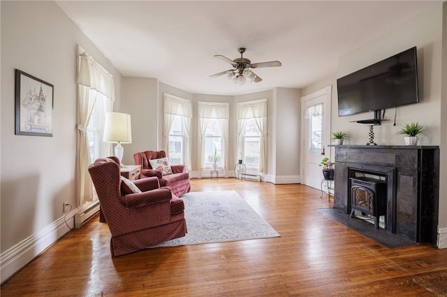 living room featuring ceiling fan, wood finished floors, and baseboard heating