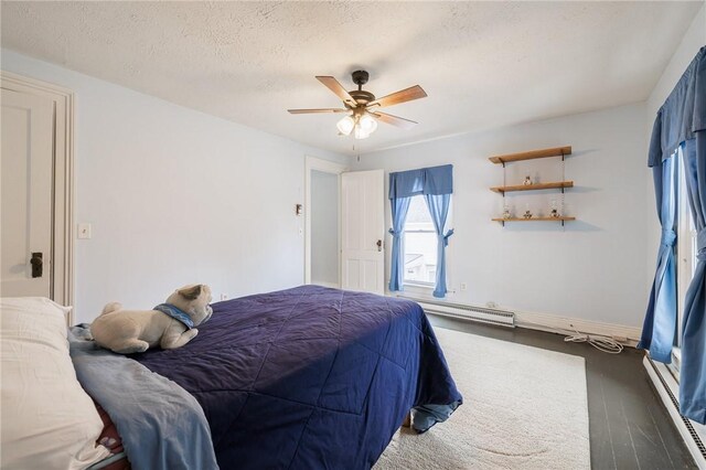 bedroom featuring a ceiling fan, wood finished floors, a textured ceiling, a baseboard radiator, and baseboards