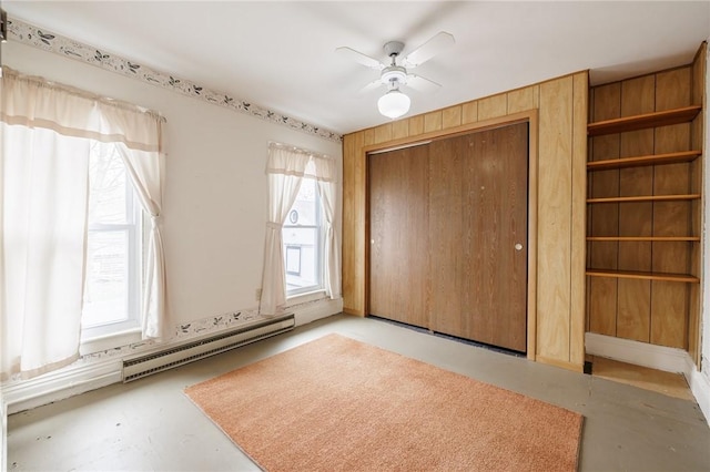 unfurnished bedroom featuring a ceiling fan, a closet, a baseboard heating unit, and finished concrete floors