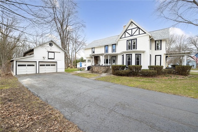 view of front facade with an outbuilding, driveway, a garage, and roof with shingles
