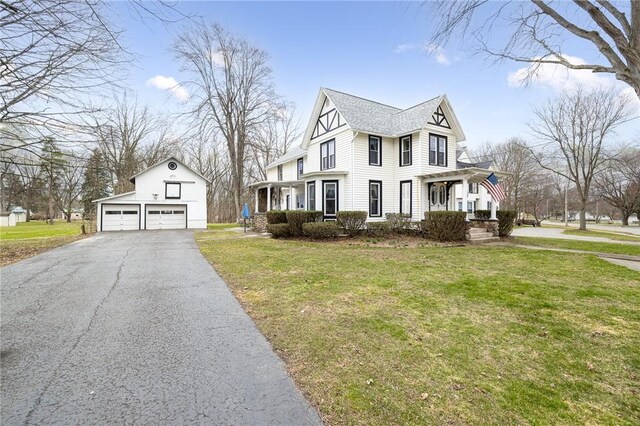 view of front of home with a front yard, an outbuilding, aphalt driveway, and a detached garage