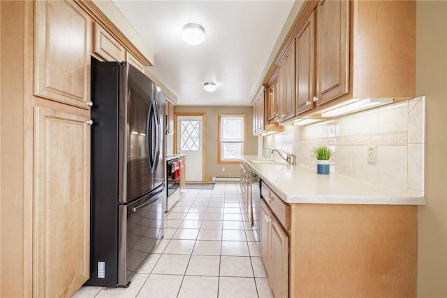 kitchen with decorative backsplash, range, light countertops, light tile patterned flooring, and freestanding refrigerator