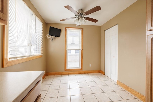 empty room with light tile patterned floors, baseboards, and ceiling fan